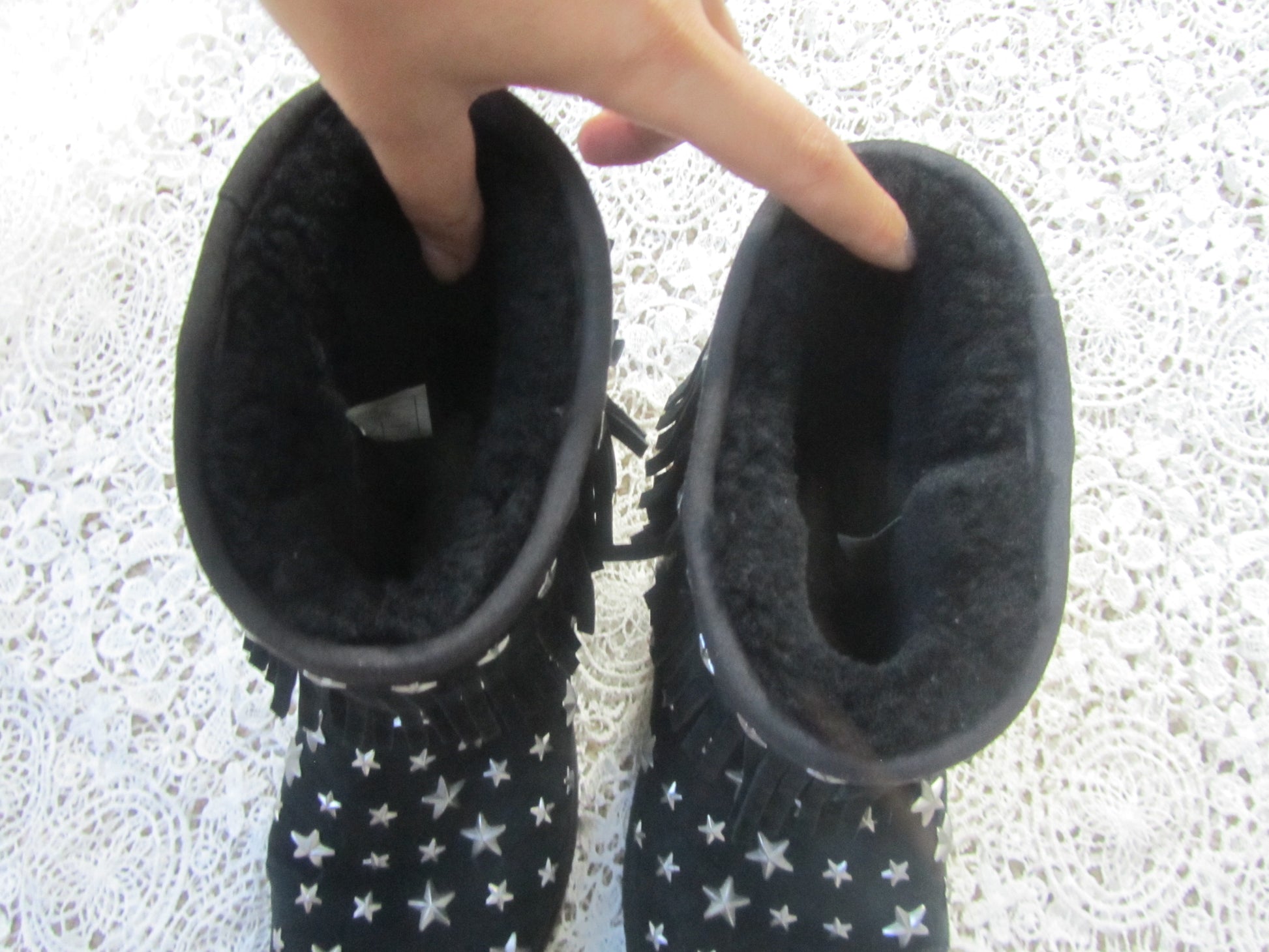 Pair of black boots with star patterns on a textured white surface