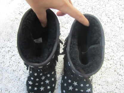 Pair of black boots with star patterns on a textured white surface