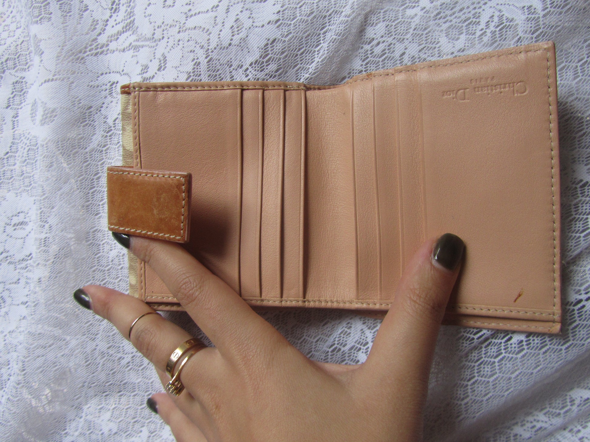 Brown leather wallet held by a hand on a white lace background