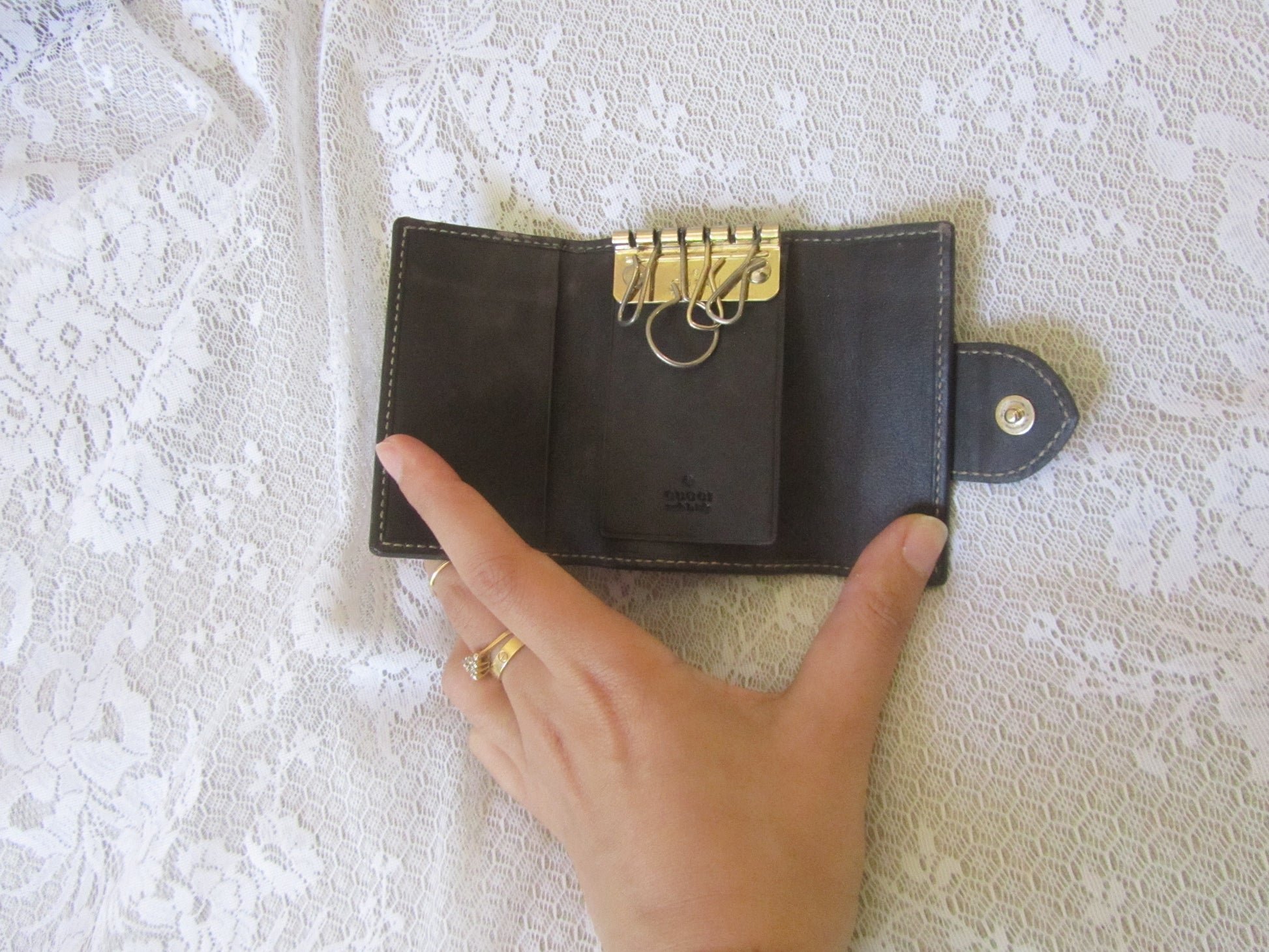 wallet with gold accents held by a hand on a textured white background