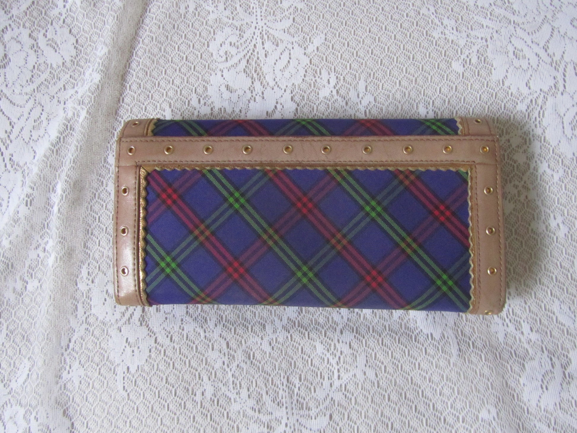 Plaid wallet with beige border on a textured white surface