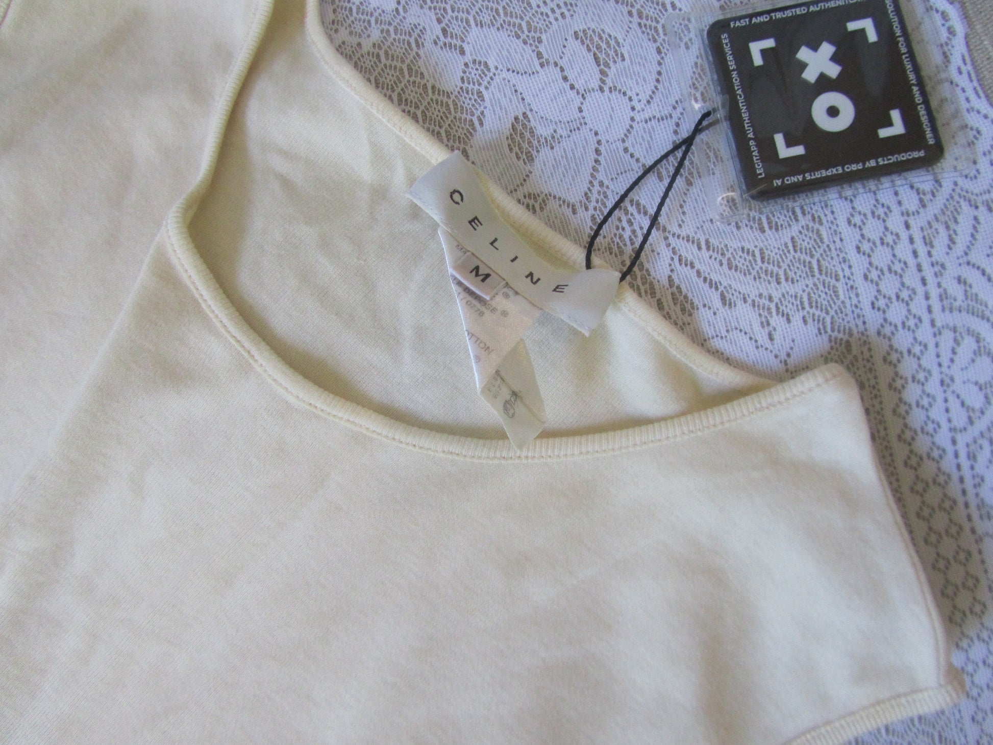 Beige tank top with a tag on a lace fabric background