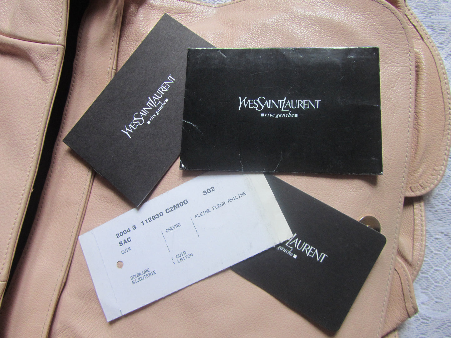Yves Saint Laurent product tags and a receipt on a beige leather surface