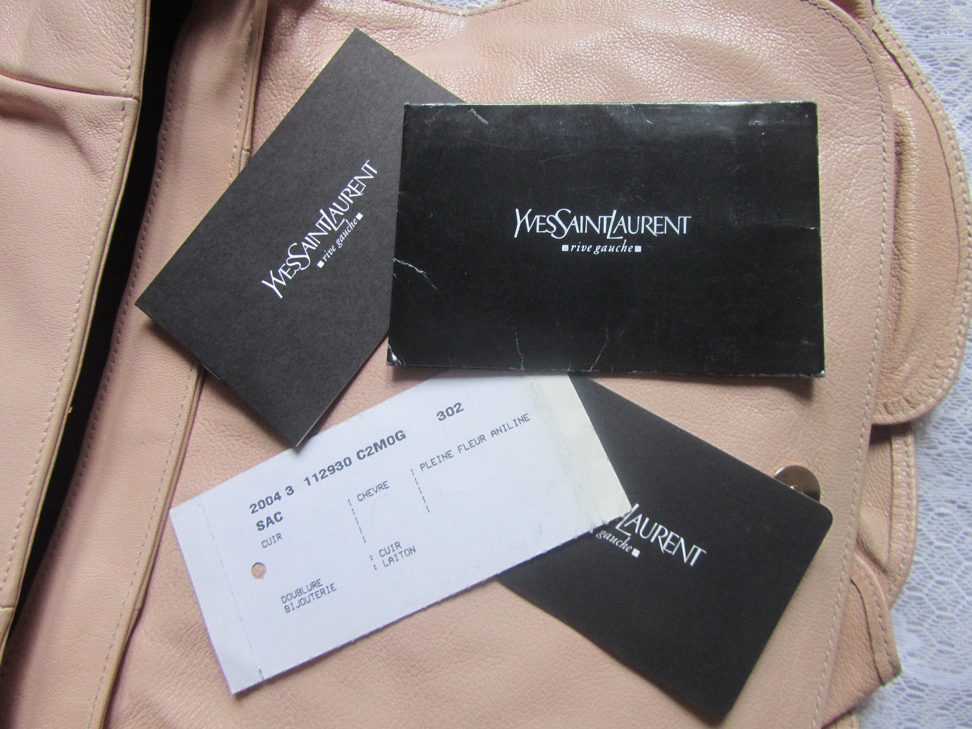 Yves Saint Laurent product tags and a receipt on a beige leather surface