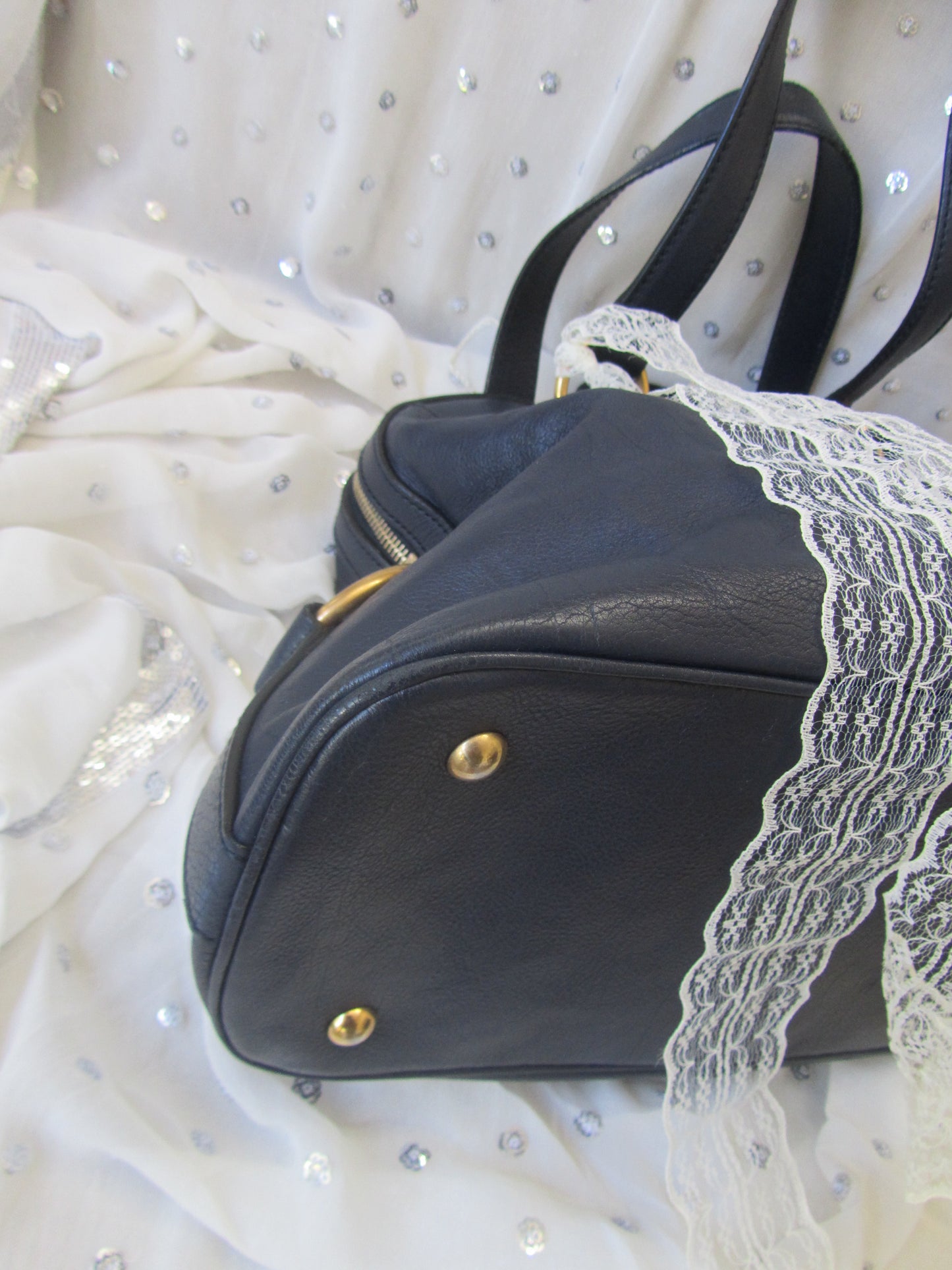 Black leather handbag with gold accents on a white fabric background