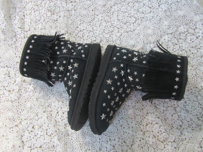 Black boots with white star patterns and fringes on a textured surface