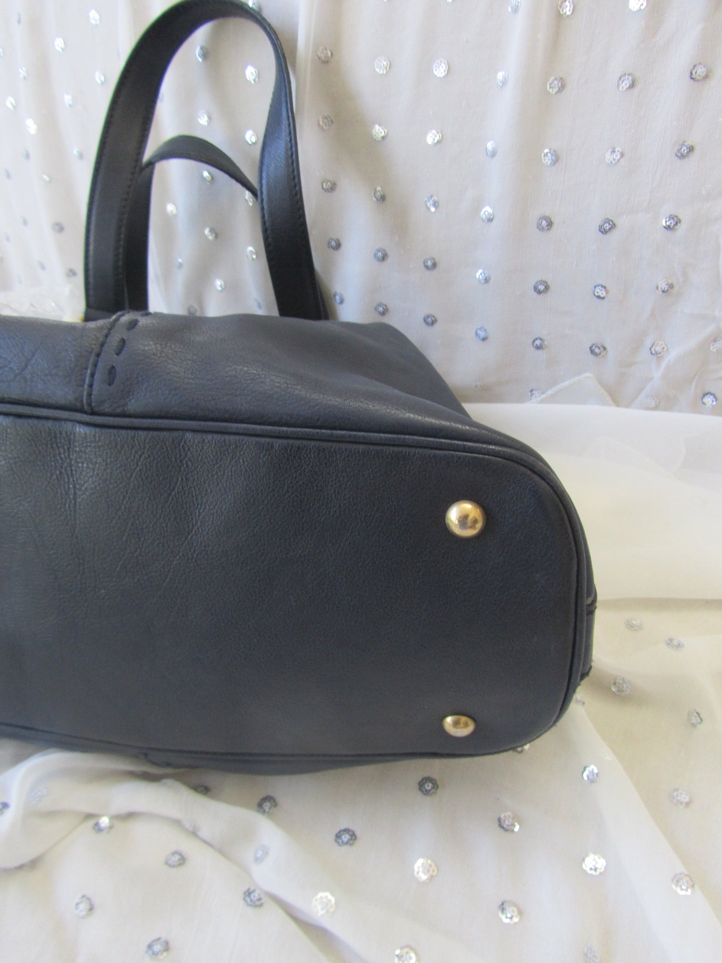 Black leather bag with gold studs on a white background
