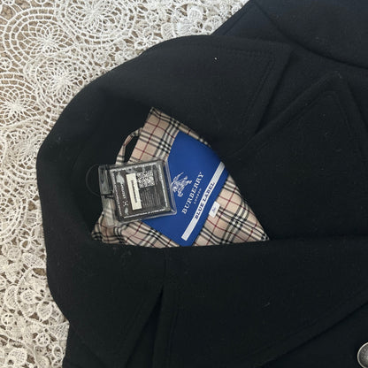 Black coat with a plaid pocket square and a blue label on a textured white background