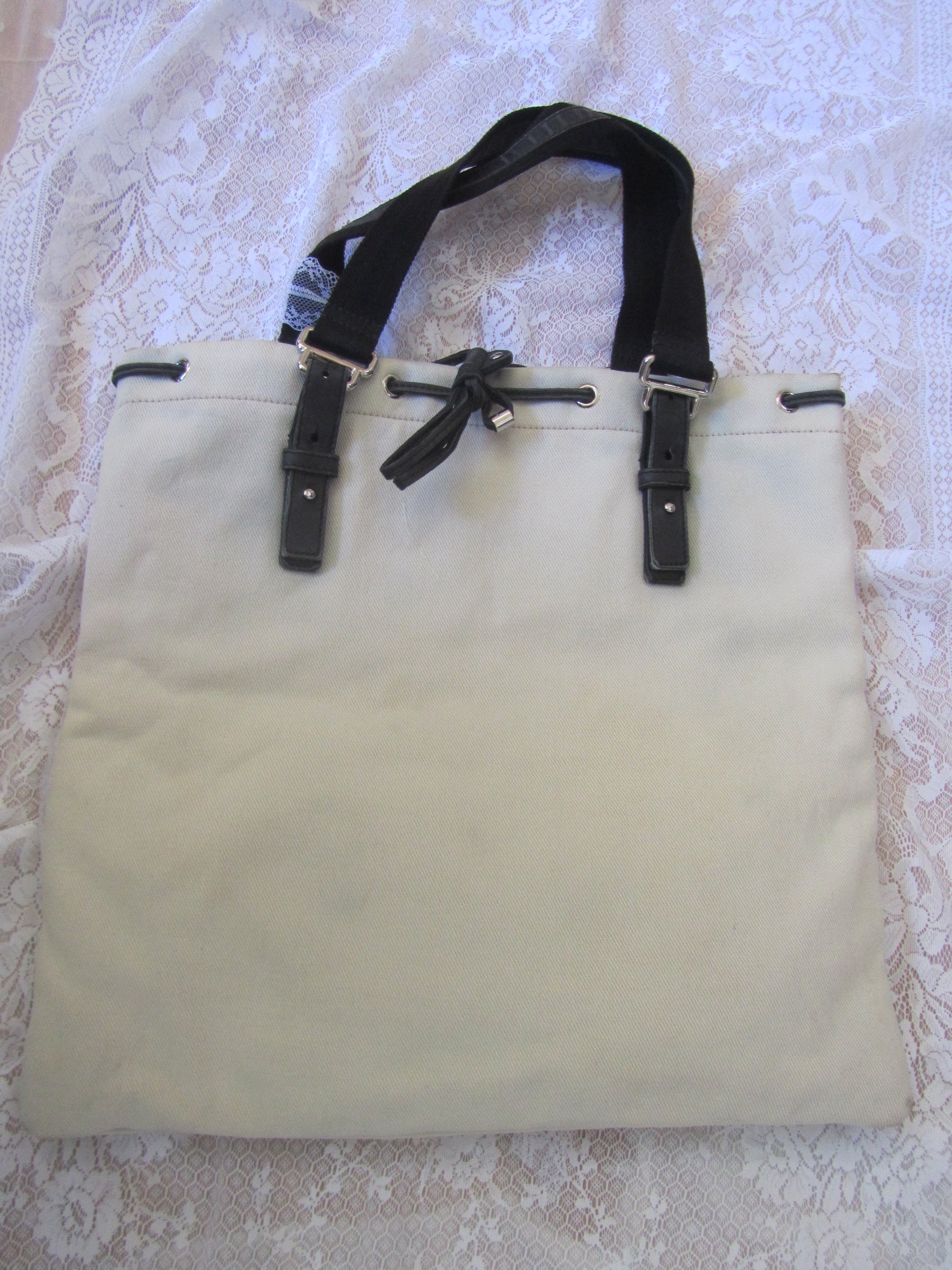 Beige tote bag with black straps on a textured white background
