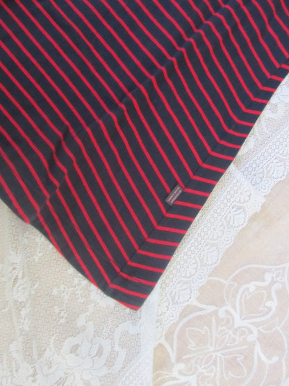 Black and red striped fabric on a textured white surface