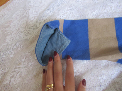 Hand holding a blue cloth over a striped fabric on a textured surface