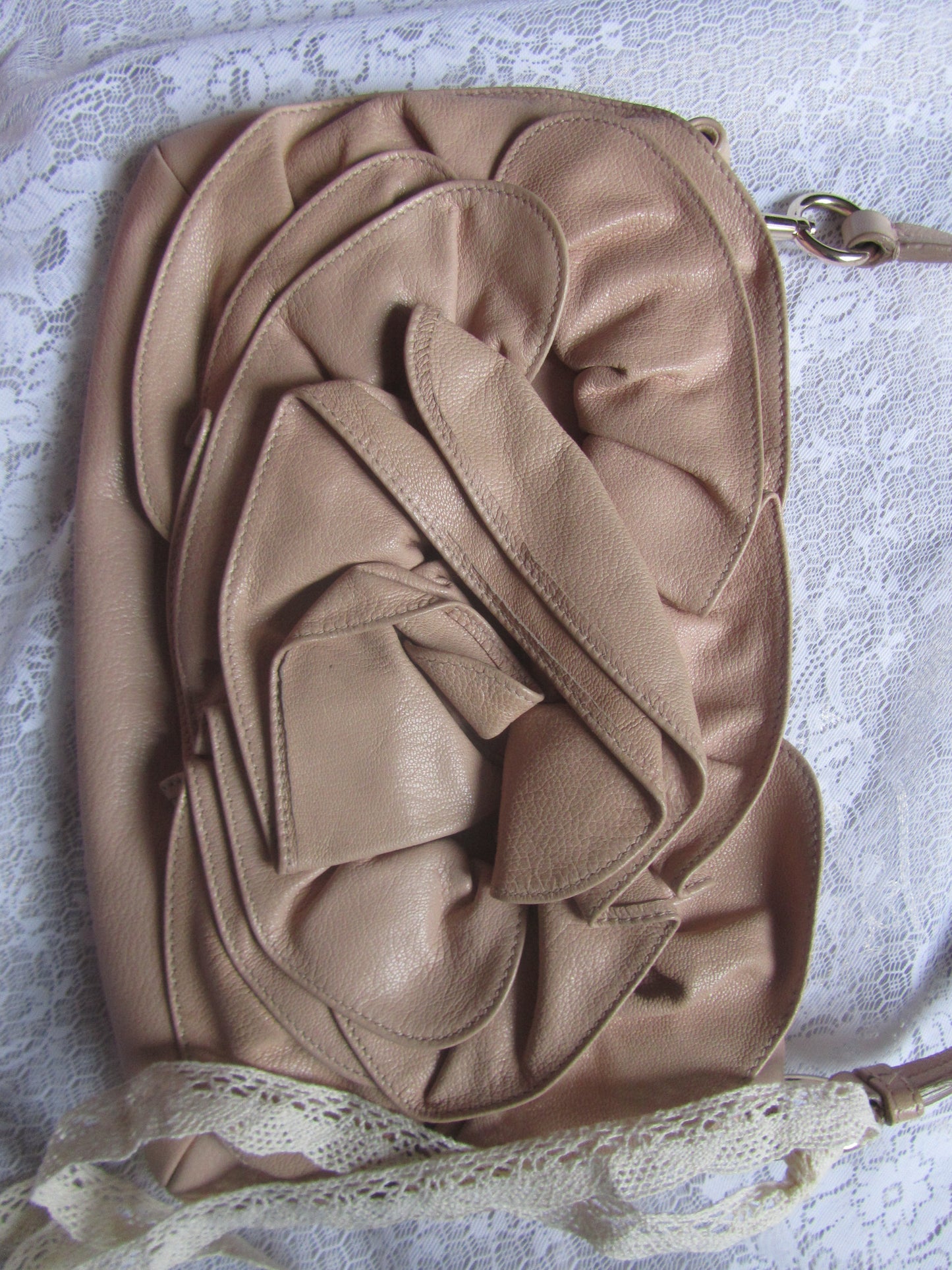 Beige handbag with ruffled design on a textured surface