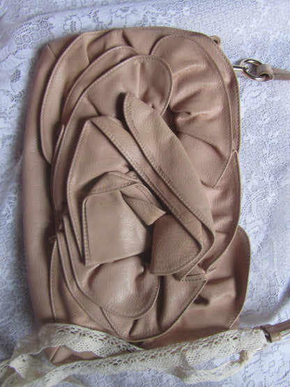 Beige handbag with ruffled design on a textured surface