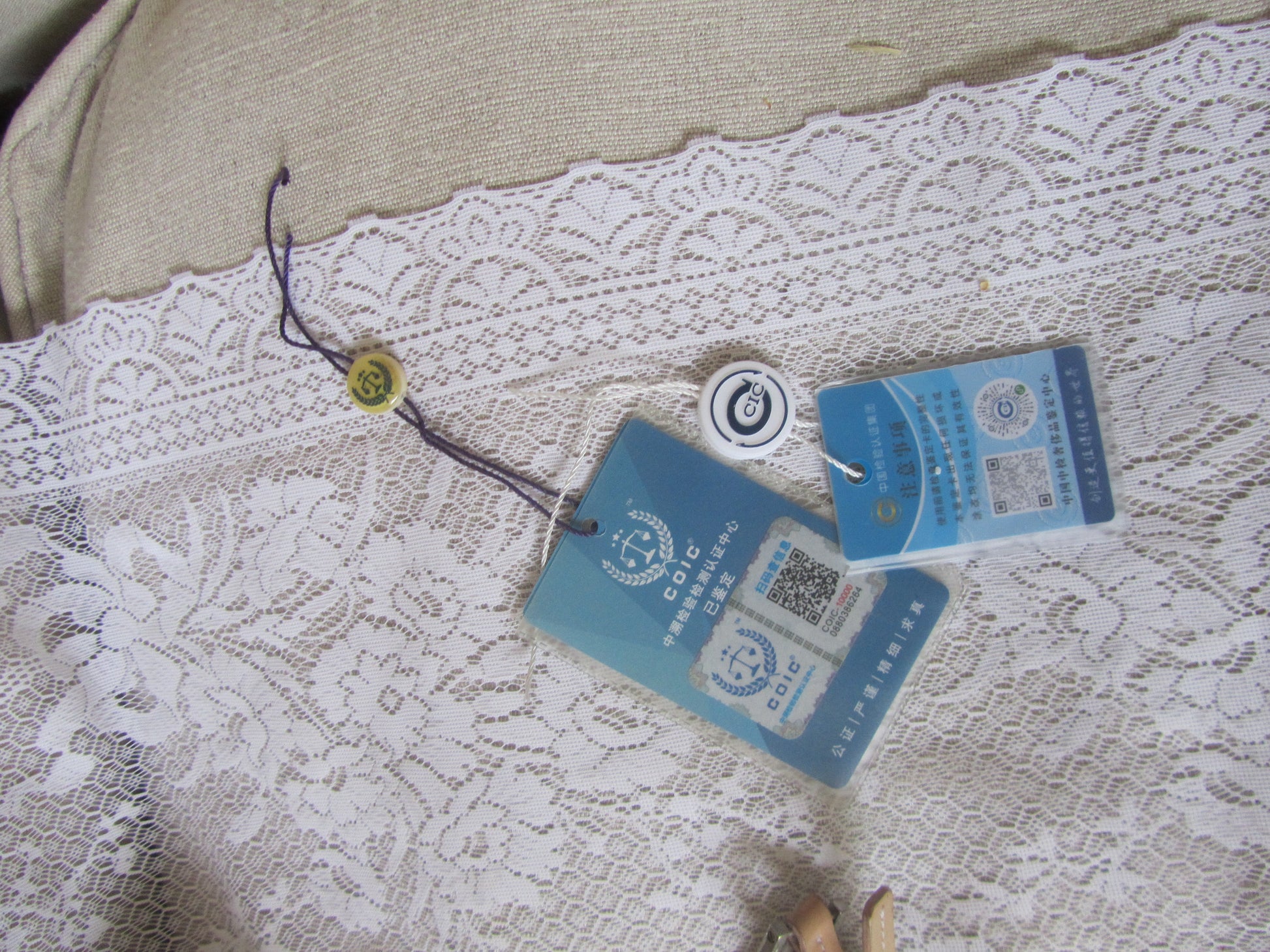 Lace fabric with tags and a button on a textured surface
