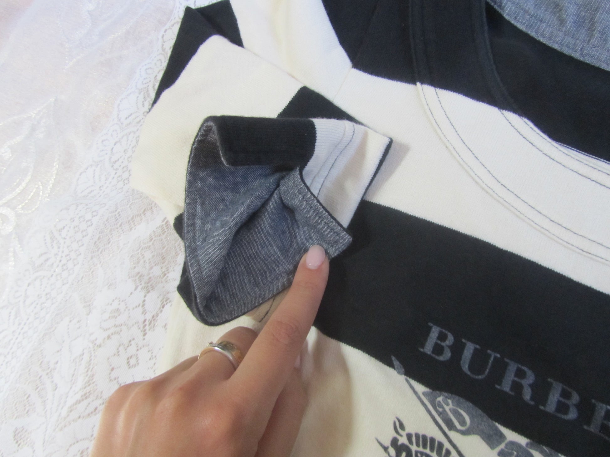 Person adjusting a Burberry garment on a white surface