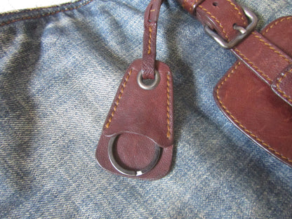 Brown leather keychain attached to a blue denim surface