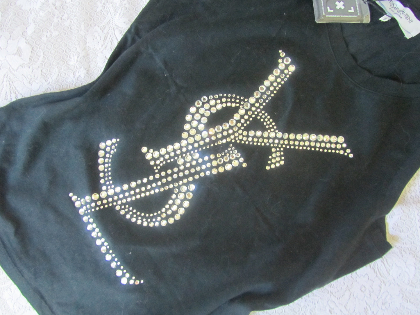 Black t-shirt with rhinestone design on a textured surface