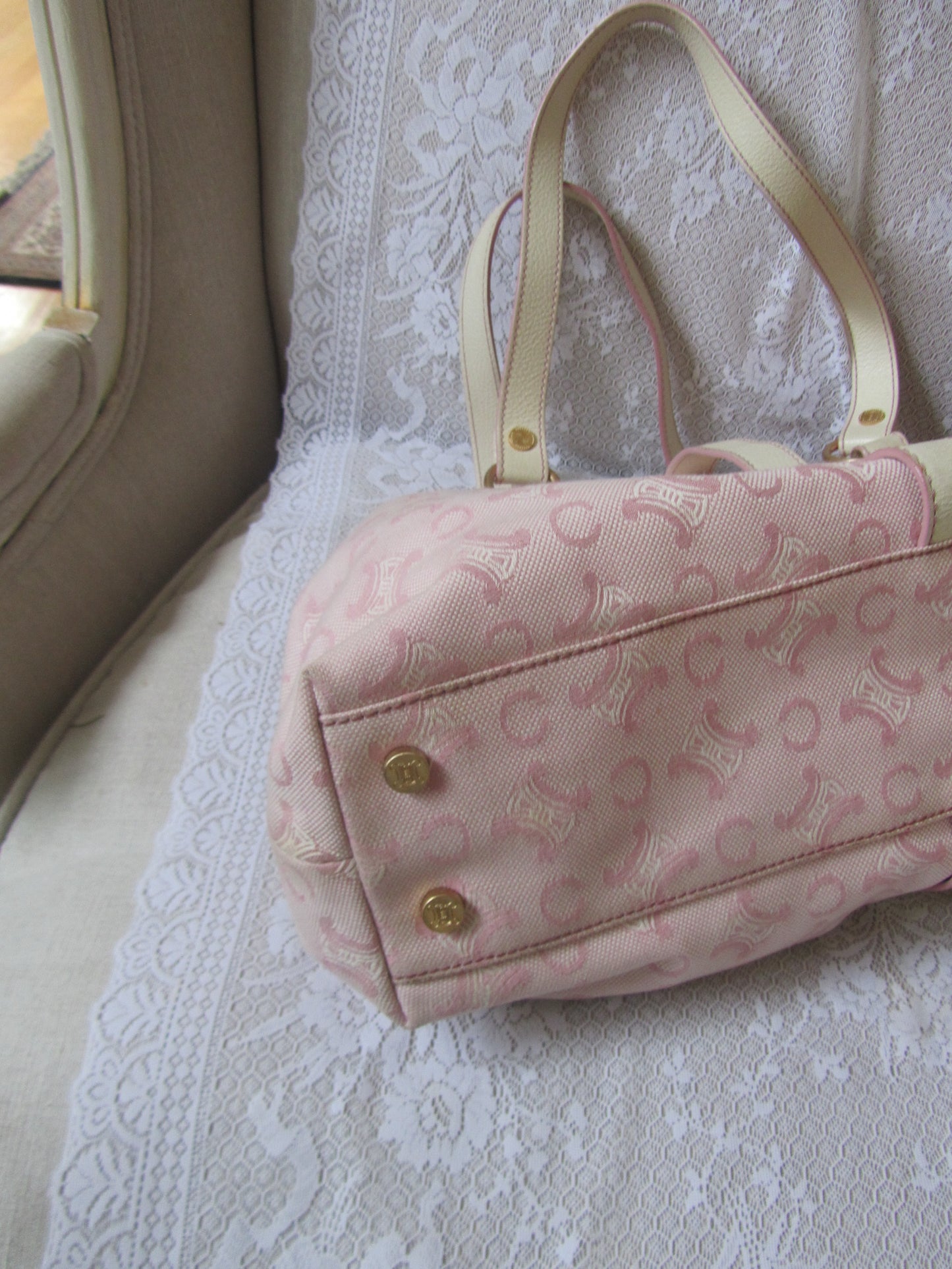 Pink handbag with gold buttons on a textured surface