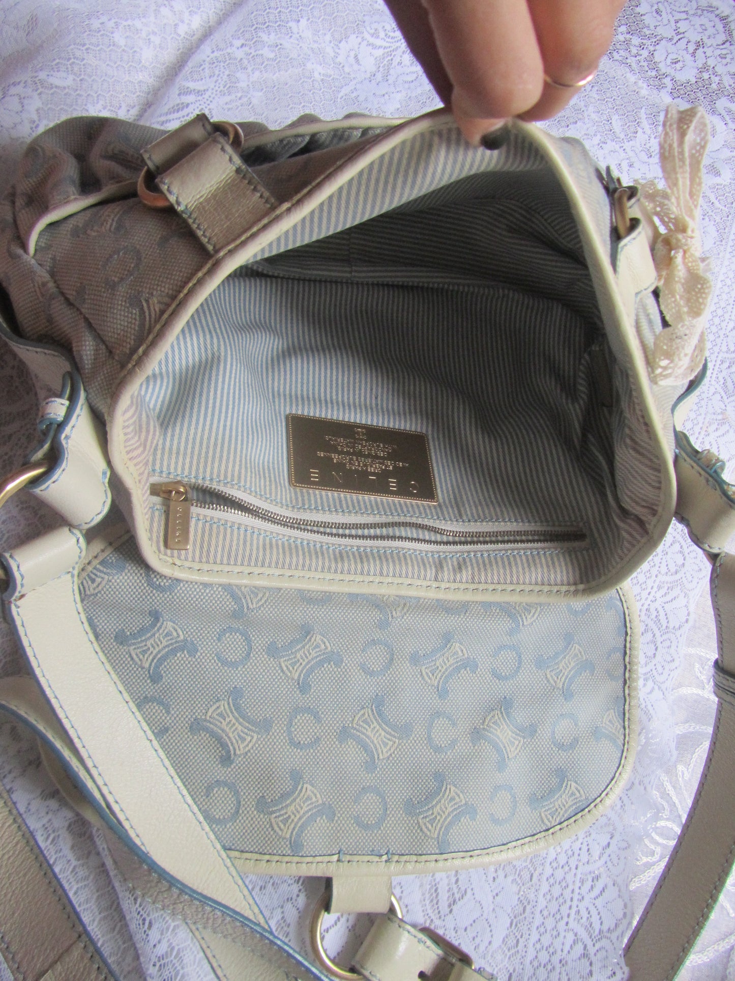 Close-up of a beige handbag with a visible brand label on a light background