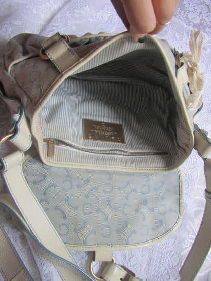 Close-up of a beige handbag with a visible brand label on a light background