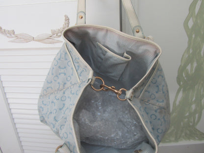 Light blue patterned handbag with a gold clasp on a neutral background