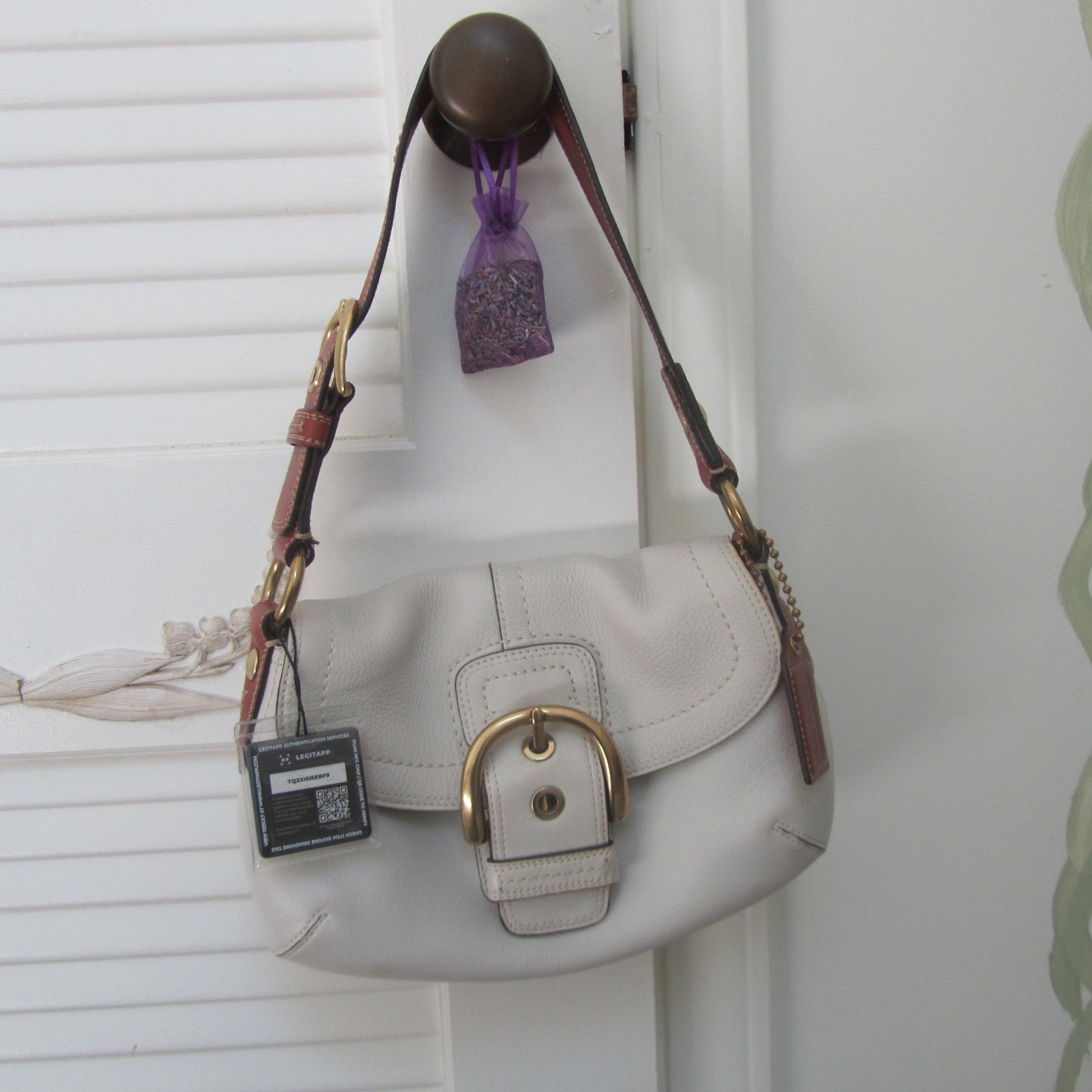 White handbag with brown strap on a white background