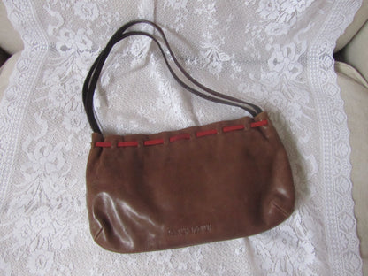 Brown handbag with red accents on a white lace fabric background