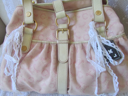 Pink handbag with lace details and gold accents on a white background