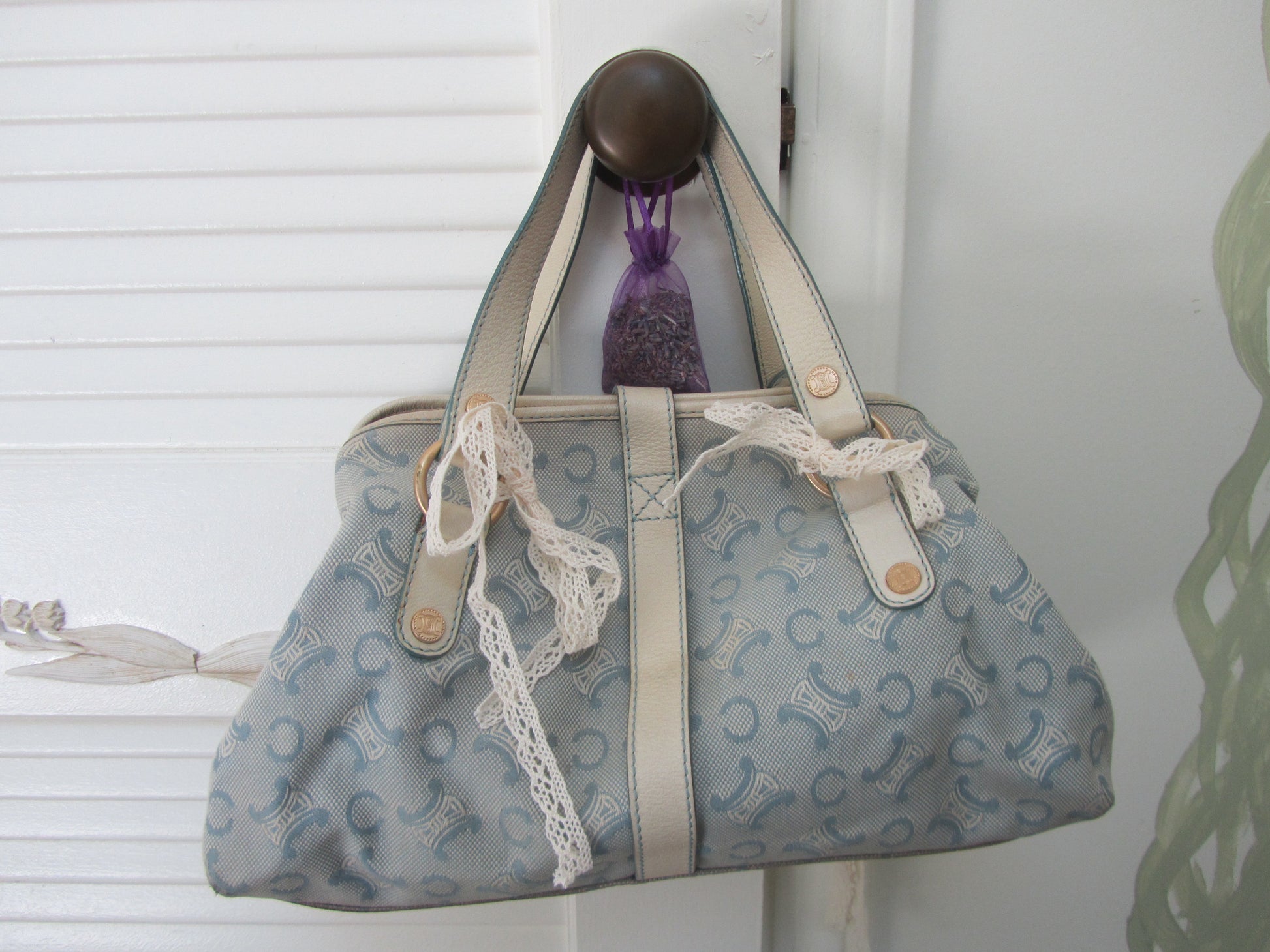 Patterned handbag with lace trim hanging on a white door handle.