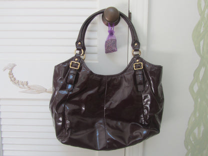 Brown handbag with gold accents hanging on a white door handle.