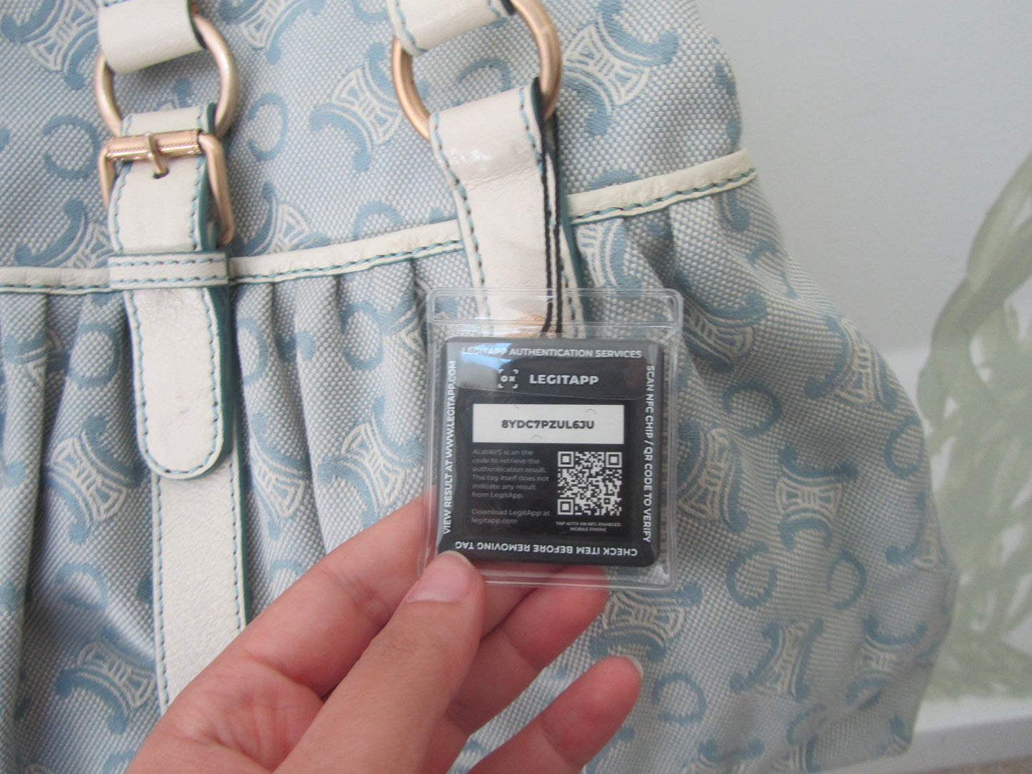 Hand holding a lectapp tag on a patterned bag