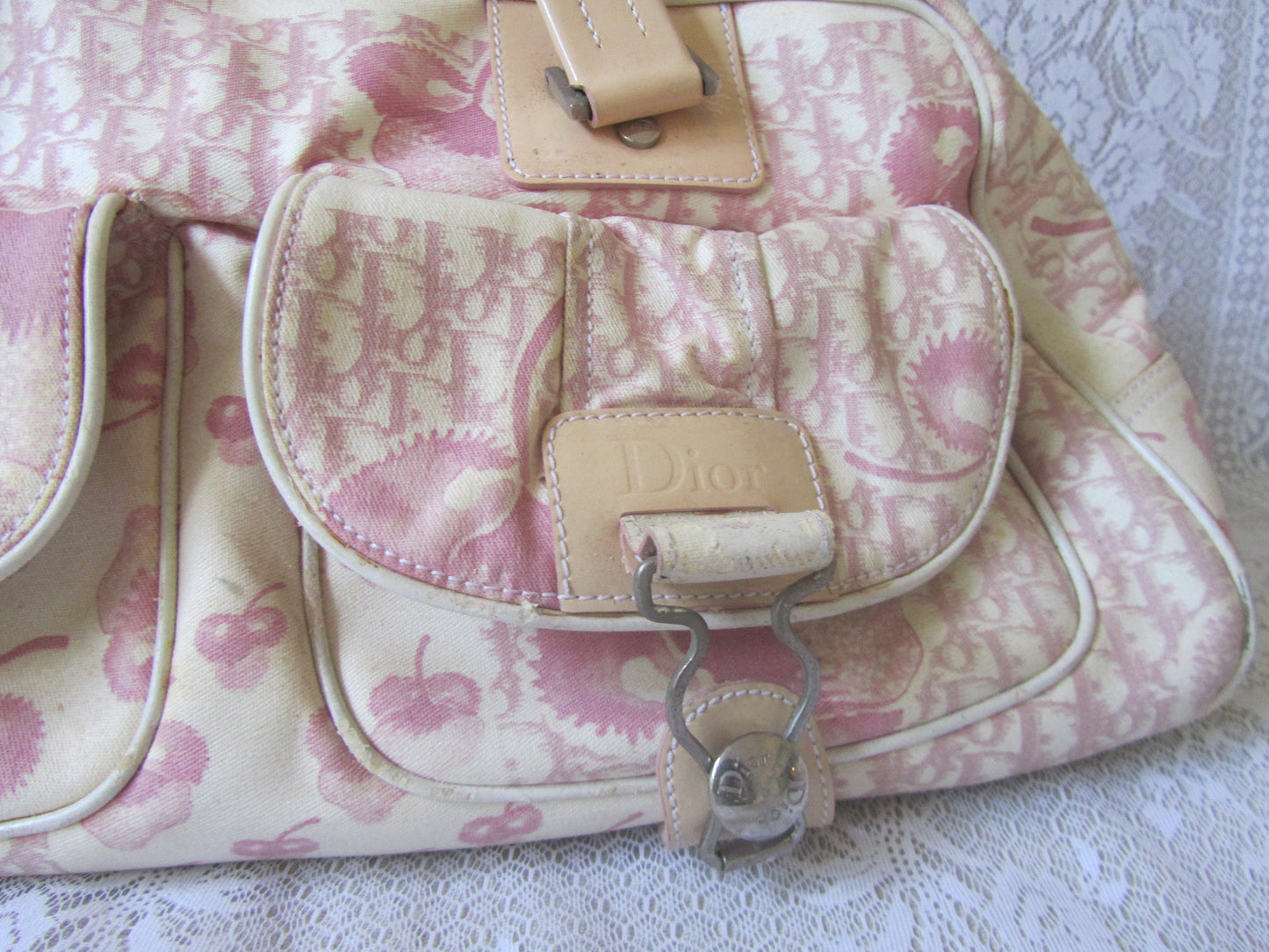 Pink floral patterned handbag with visible brand logo on a textured surface