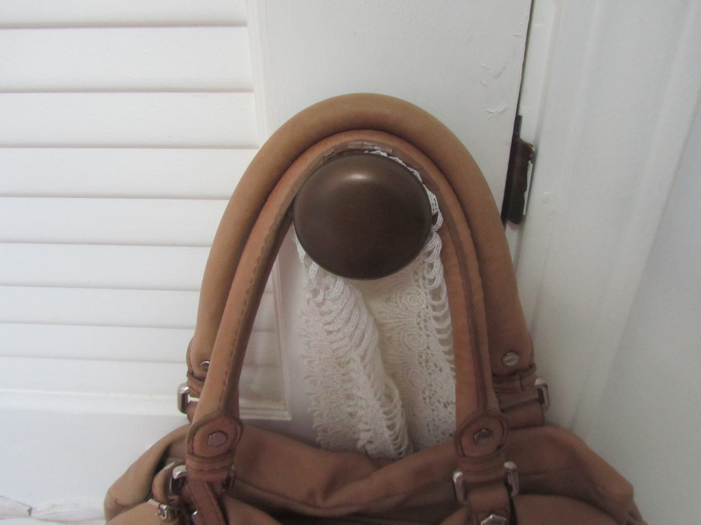 Brown leather handbag with a metal clasp on a white background