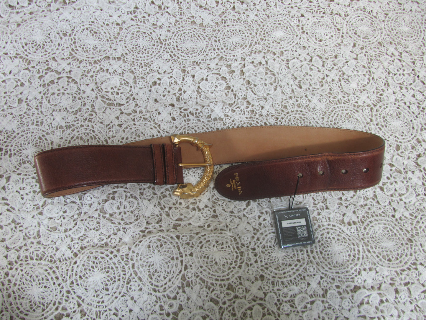 brown prada belt with gold buckle and gold detailing on lace background