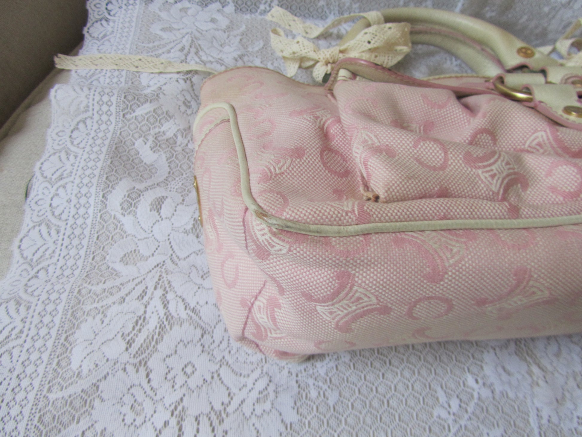 Pink handbag with lace detailing on a lace surface