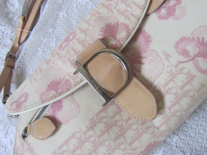 Floral-patterned handbag with a beige strap and silver buckle on a textured white background