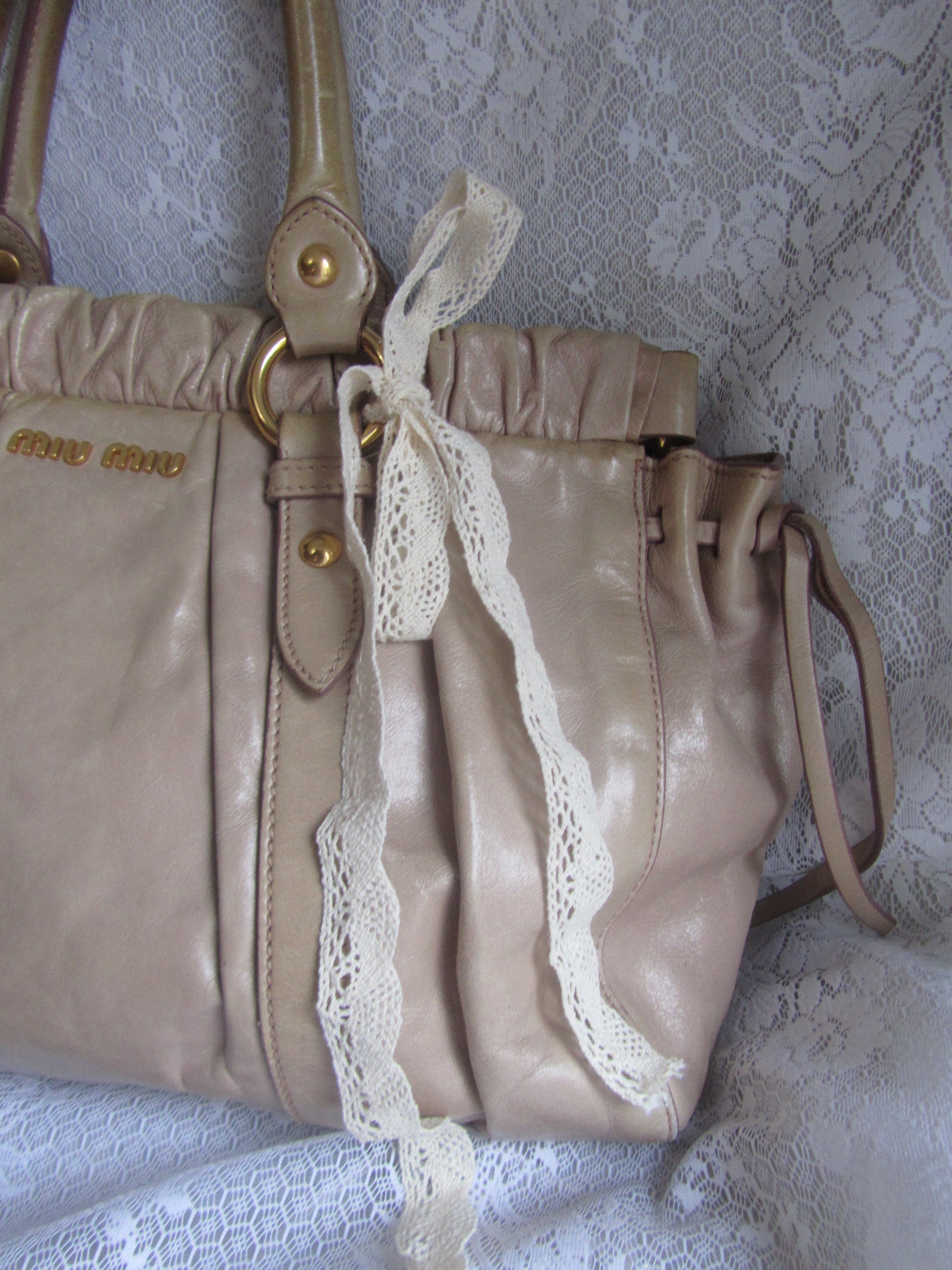 Beige handbag with lace trim on a textured white background