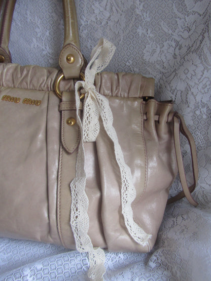 Beige handbag with lace trim on a textured white background