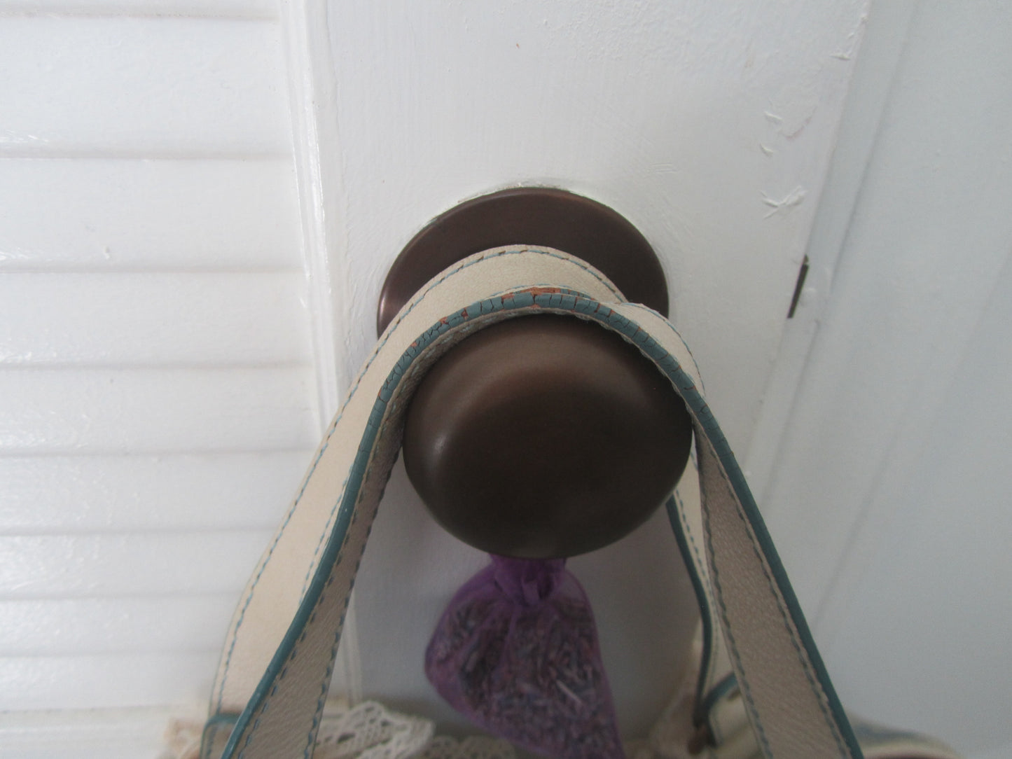 Close-up of a brown doorknob on a white door with a purple object attached.