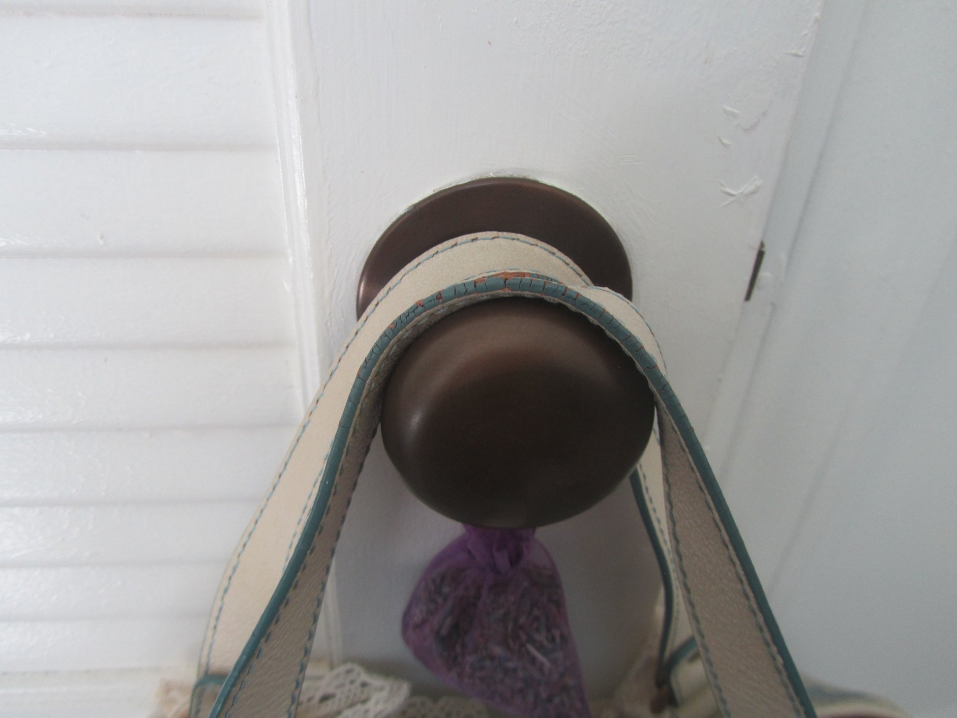 Close-up of a brown doorknob on a white door with a purple object attached.