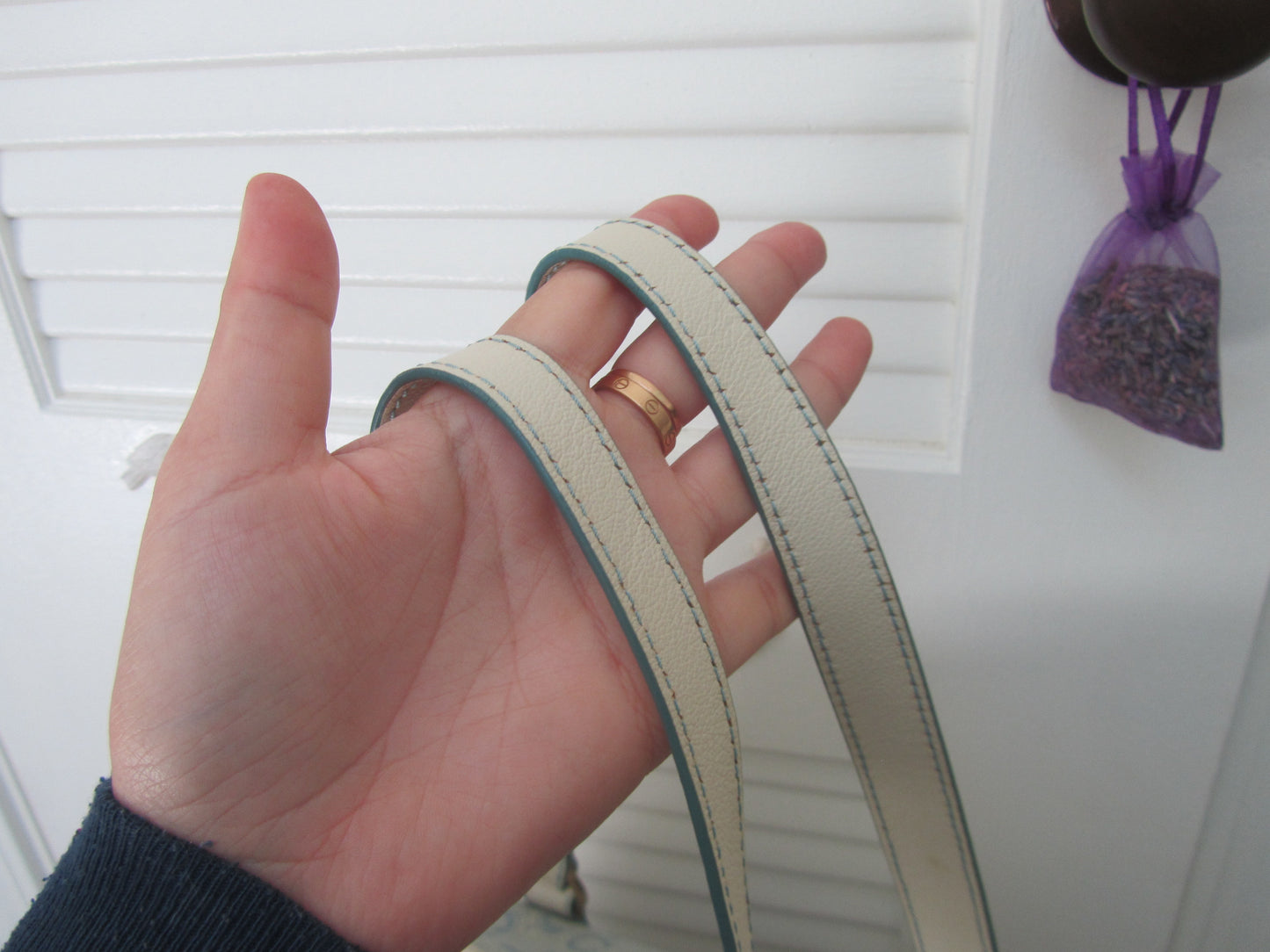 Hand holding two beige ribbons with a white background