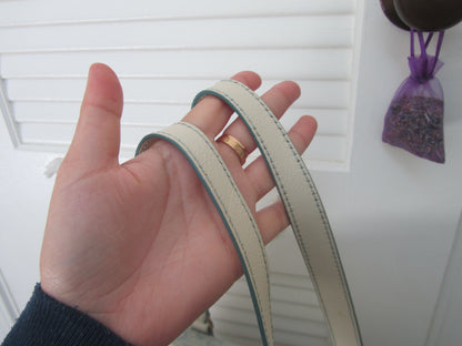 Hand holding two beige ribbons with a white background