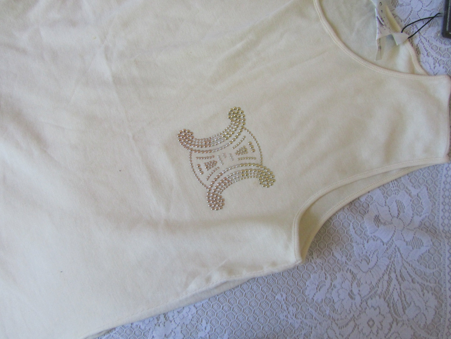 Beige top with green embroidery on a textured surface