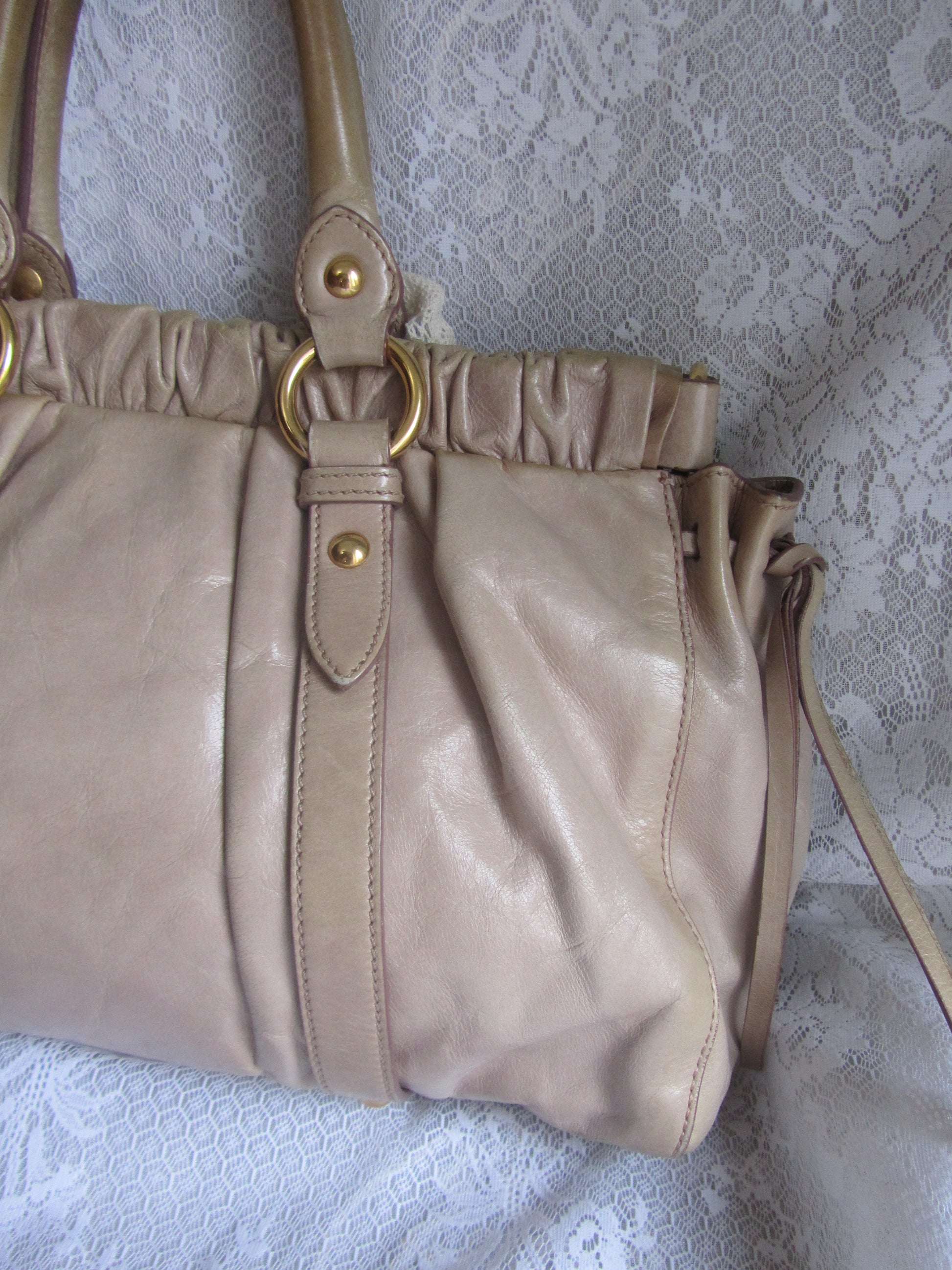 Beige handbag with gold accents on a textured white background
