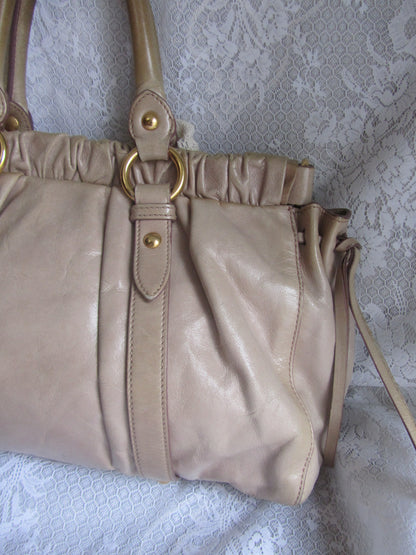 Beige handbag with gold accents on a textured white background