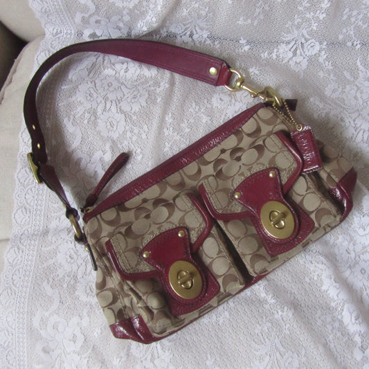 Coach handbag with red accents on a textured white surface
