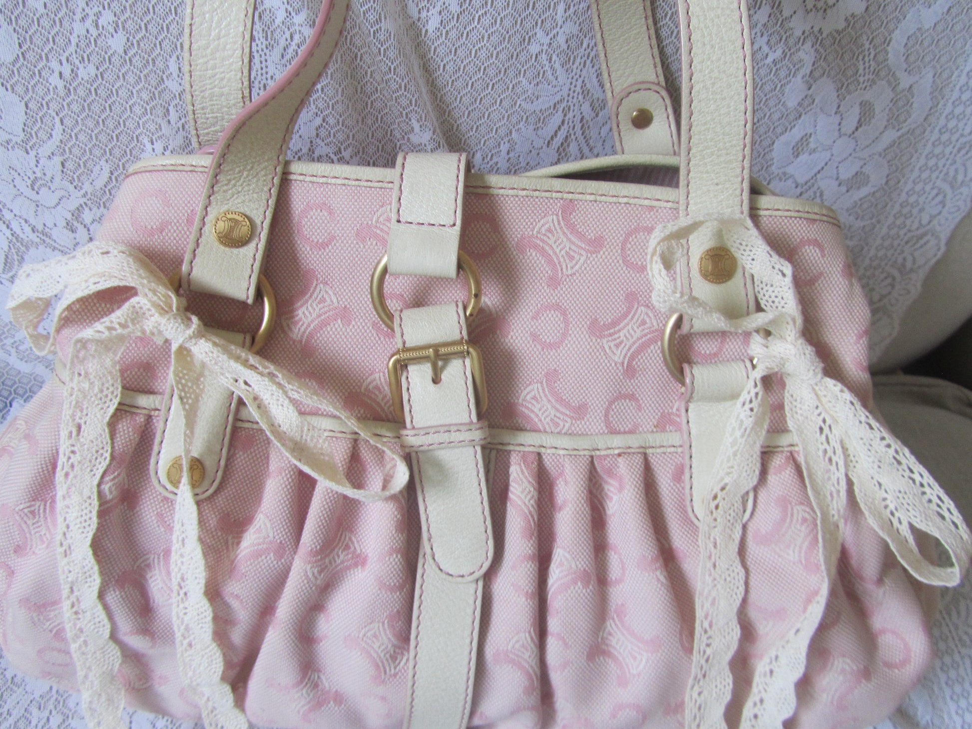 Pink handbag with lace straps on a textured white background