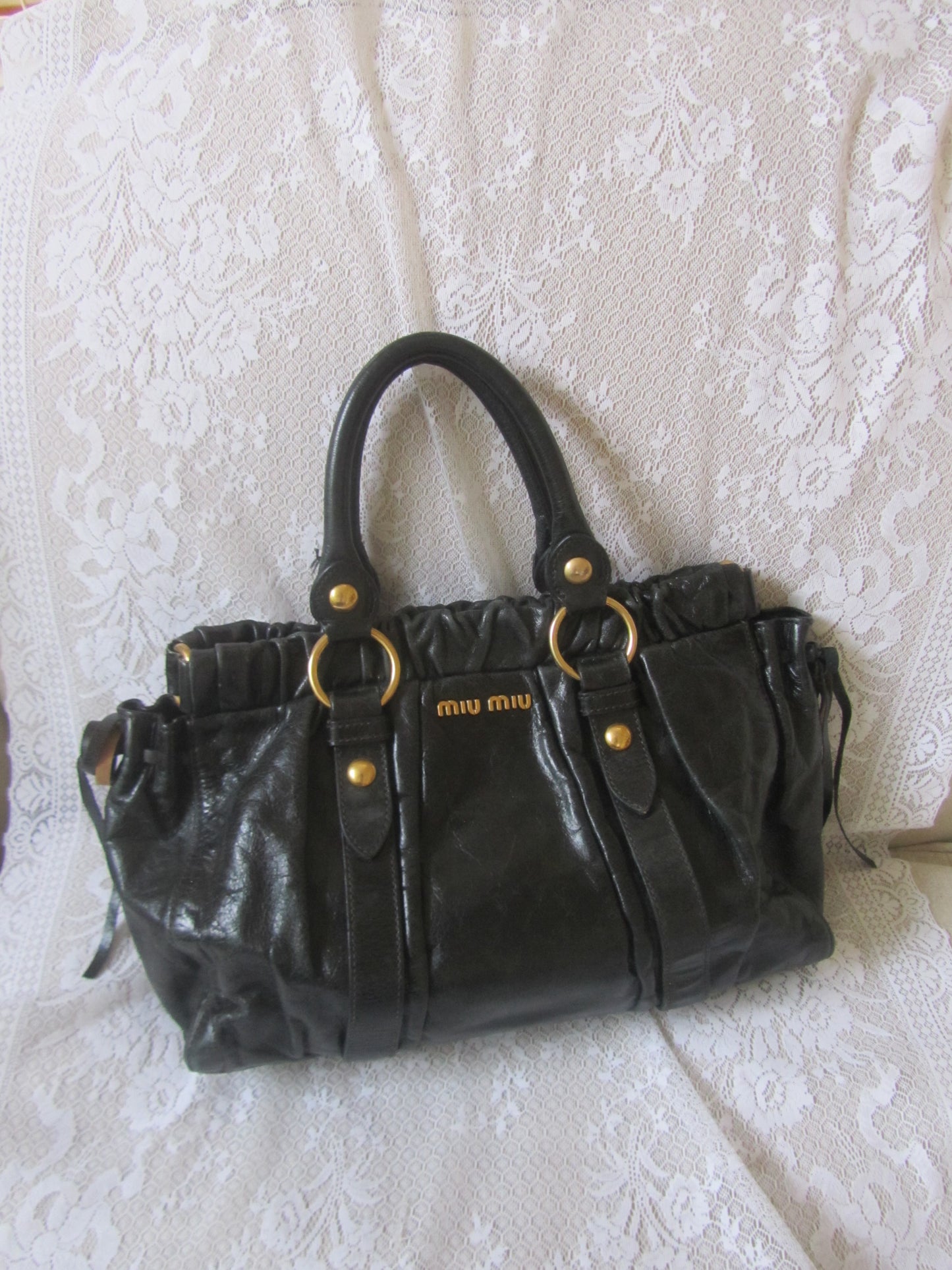Black handbag with gold accents on a textured white surface