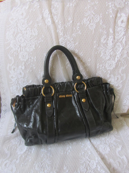 Black handbag with gold accents on a textured white surface