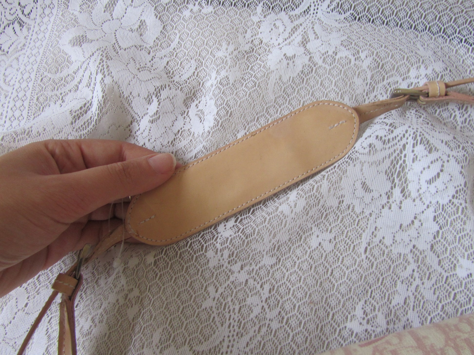 Hand holding a leather strap against a lace background